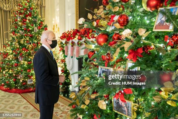 President Joe Biden looks at a Christmas tree decorated with photos of White House first families in the State Dining Room, Monday, November 29, 2021.