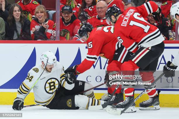 Jakub Lauko of the Boston Bruins reacts after being hit in the eye with a skate by Jason Dickinson of the Chicago Blackhawks during the third period...