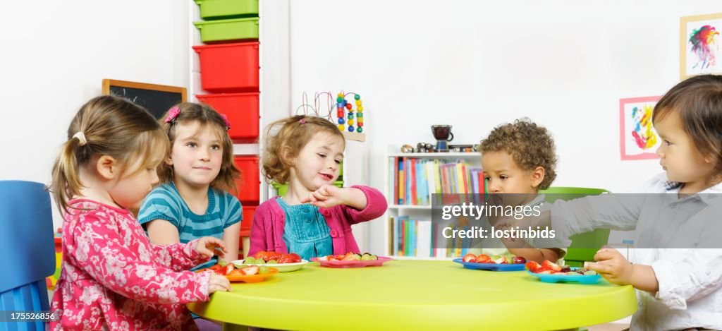 Group Of Little Children Having Fruit At Nursery