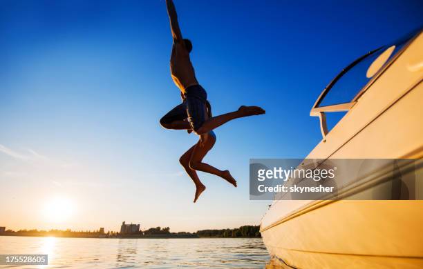 deux personnes sautant dans l'eau contre le ciel bleu. - blue sky friends photos et images de collection