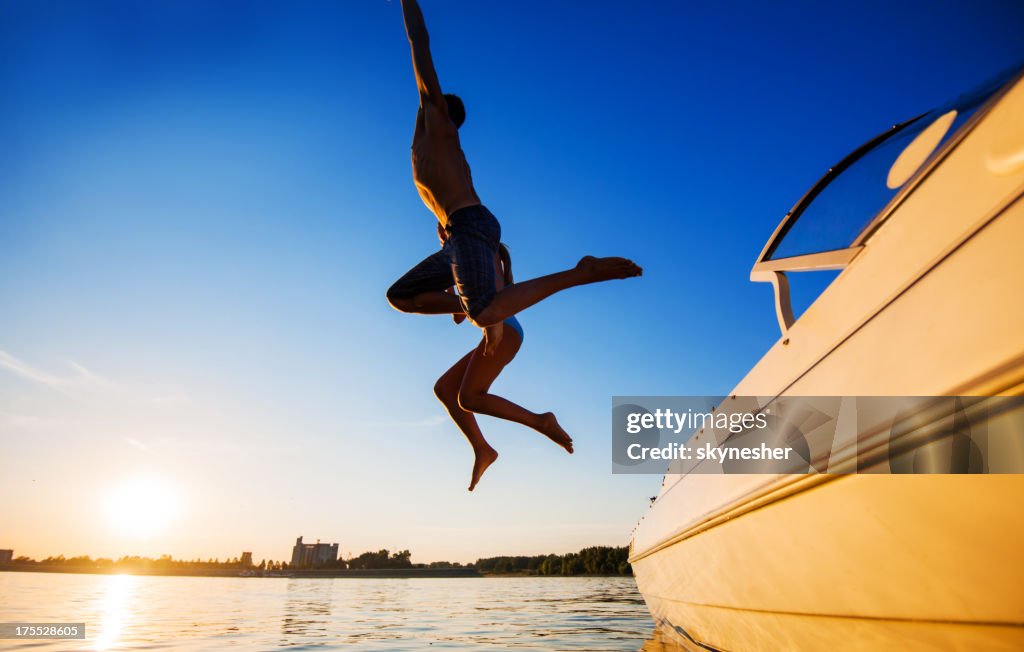 Two people jumping in water against the blue sky.
