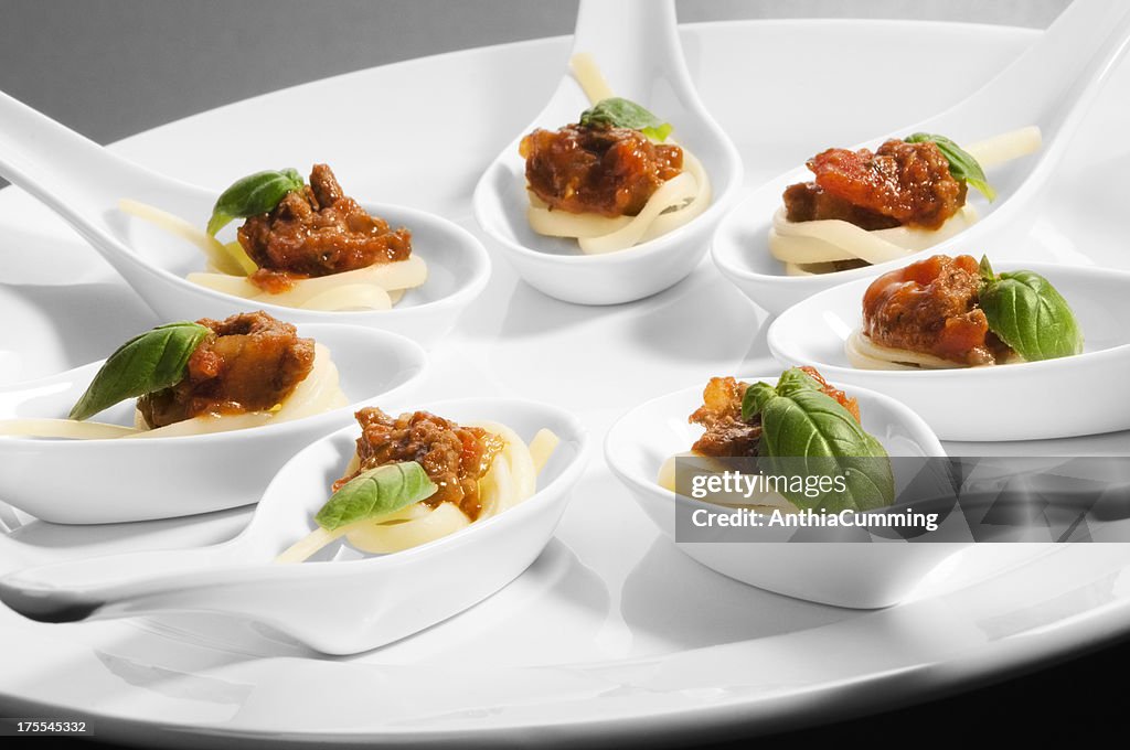 Individual canape spoons on a white serving plate