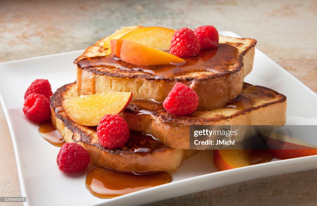 Pain perdu aux fruits frais et sirop sur un plan en marbre.