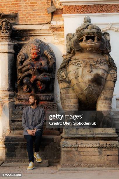 man sitting near the  statue in bhaktapur - indian crutch stock pictures, royalty-free photos & images