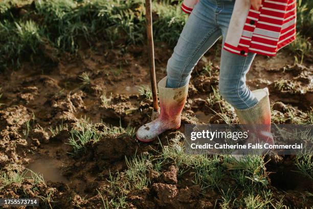 close-up of a child wearing glittery wellington boots and squelching through thick mud in a field - young thick girls stock-fotos und bilder