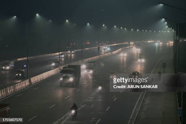 Vehicles move along a road in smoggy conditions in New Delhi on October 31, 2023.