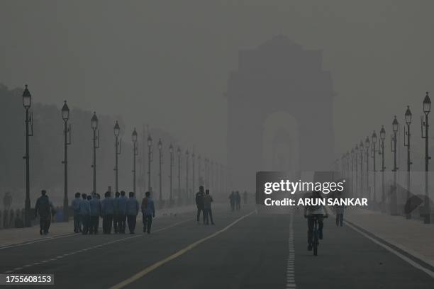 People walk in smoggy conditions at India Gate in New Delhi on October 31, 2023.