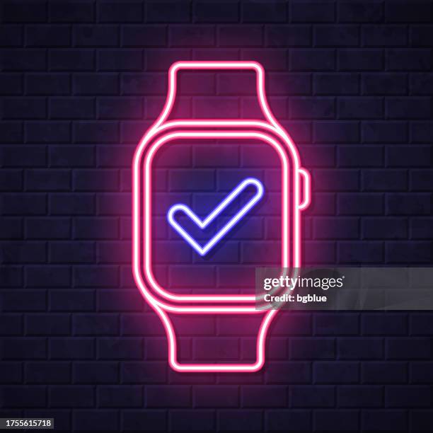 smartwatch with check mark. glowing neon icon on brick wall background - looking over wall stock illustrations