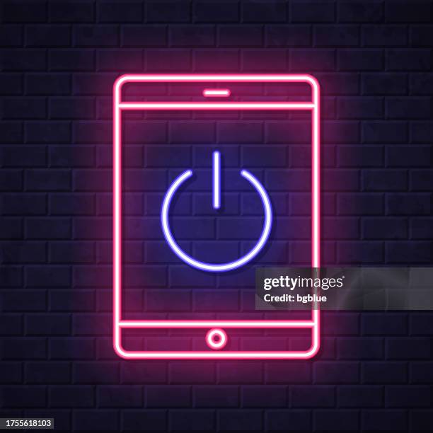 tablet pc with power button. glowing neon icon on brick wall background - pushing against wall stock illustrations