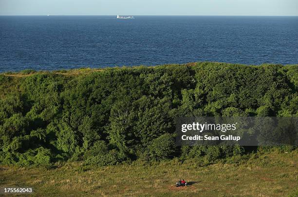 Couple sits on a bench in grass that covers a crater created by a 5-ton bomb, the largest non-nuclear explosive used in World War II and detonated by...