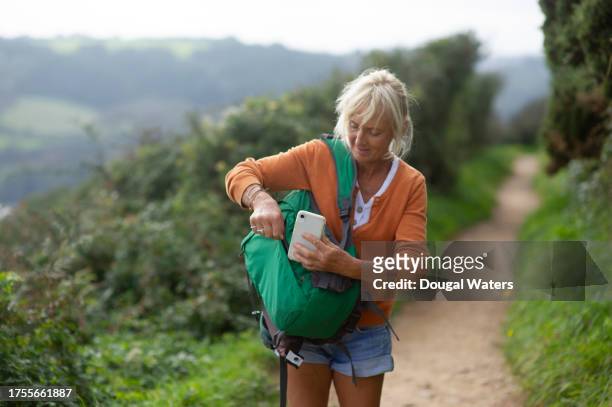 taking her smart phone from her backpack on a walk - white shorts stock pictures, royalty-free photos & images