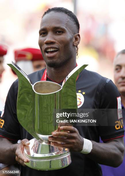 Galatasaray's Ivorian striker Didier Drogba with the trophy after scoring his side's two goals in the pre-season friendly football match between...