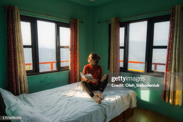 woman sitting on bed and reading a book - glimpses of daily life in nepal stock pictures, royalty-free photos & images