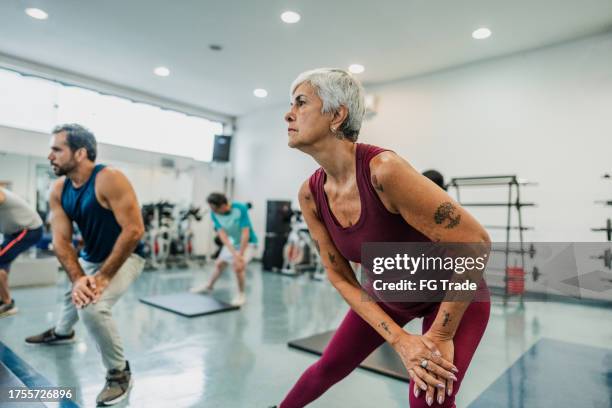 senior woman stretching in an exercise class at the gym - aeróbica imagens e fotografias de stock