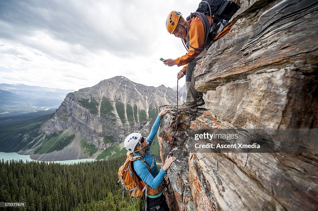 Climber takes picture of teammate ascending cliff