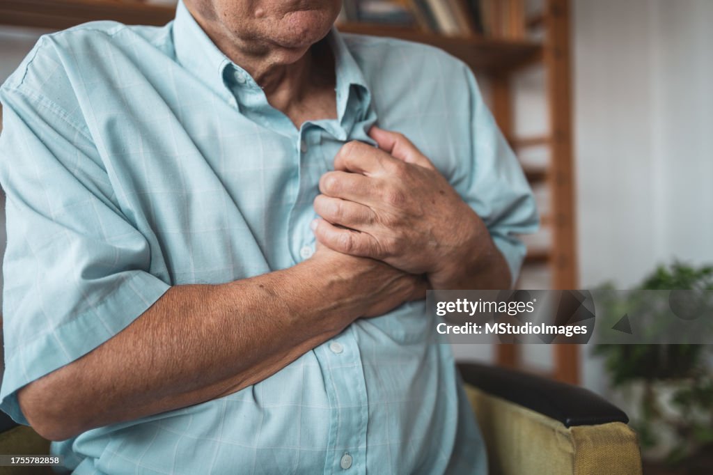 Close-up of an elderly man's hand held his chest in pain