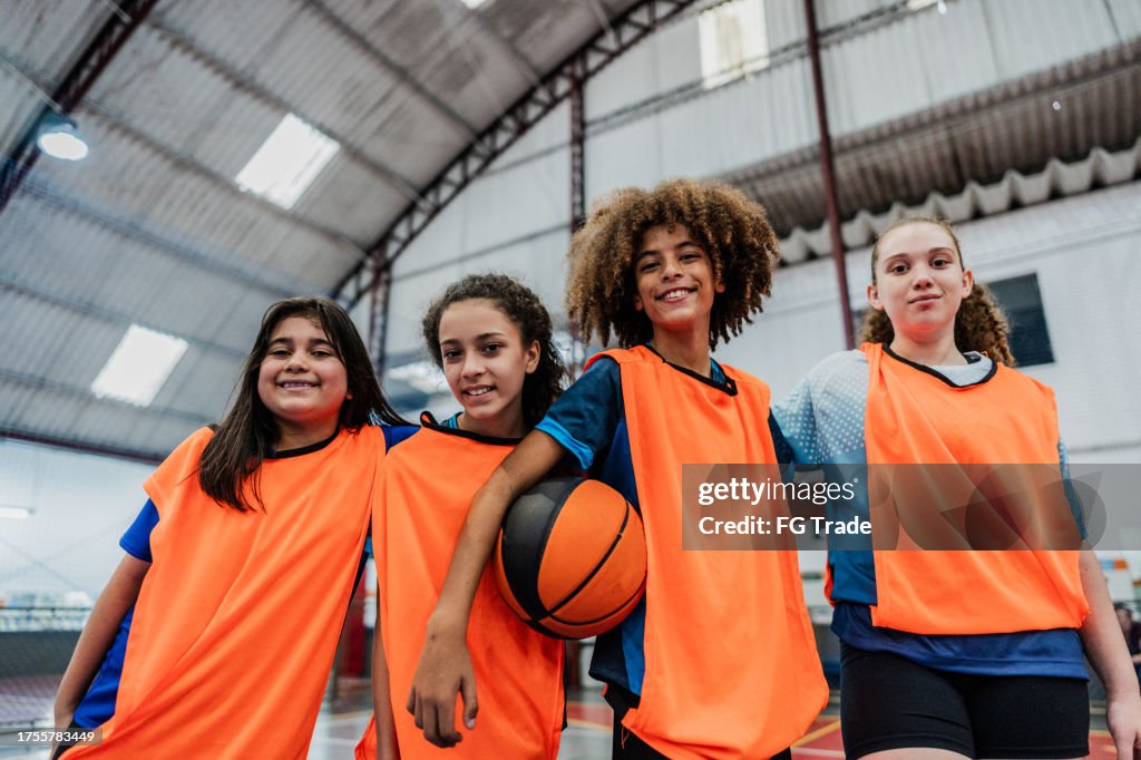 Portrait of children holding a basketball ball at a sports court