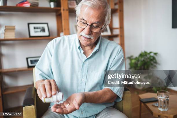 senior man relieving disease symptoms taking a painkiller pill - taking pills stock pictures, royalty-free photos & images
