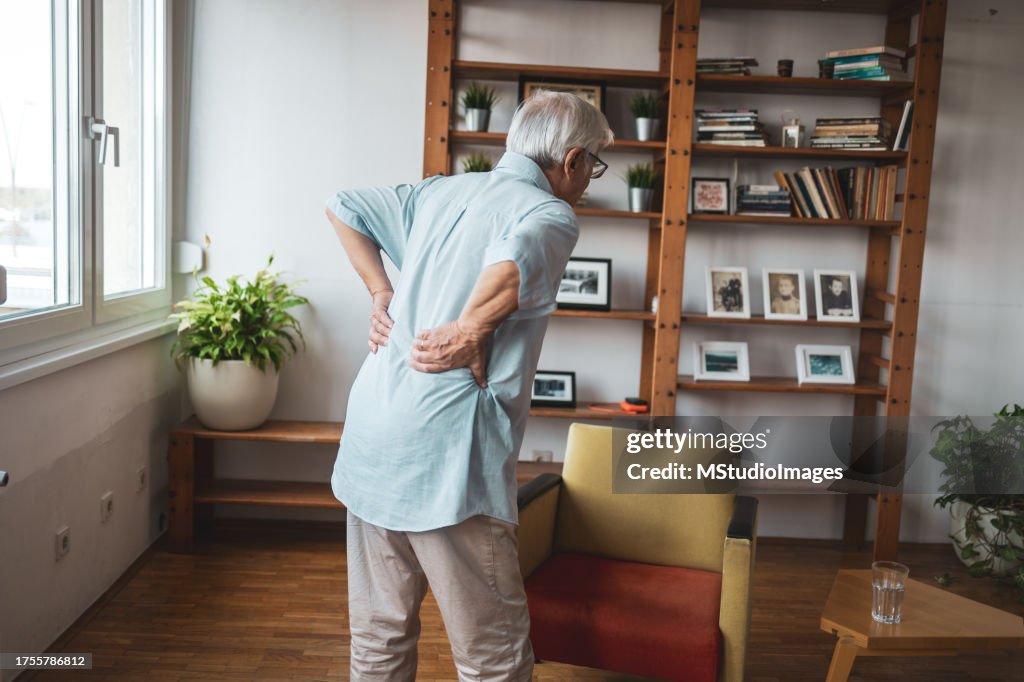 Unknown senior man holding hands on his back