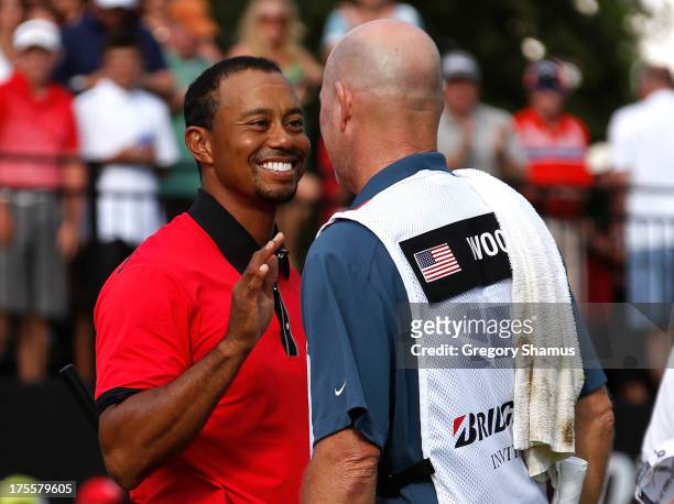 Tiger Woods smiles and speaks with caddie Joe LaCava after the Final Round of the World Golf Championships-Bridgestone Invitational at Firestone...