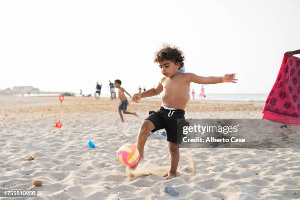 a child playing with a ball on the beach - kicking sand stock pictures, royalty-free photos & images