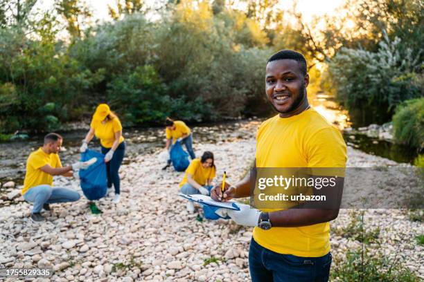 young male nature conservation volunteer using a checklist on the riverbank - water margin stock pictures, royalty-free photos & images