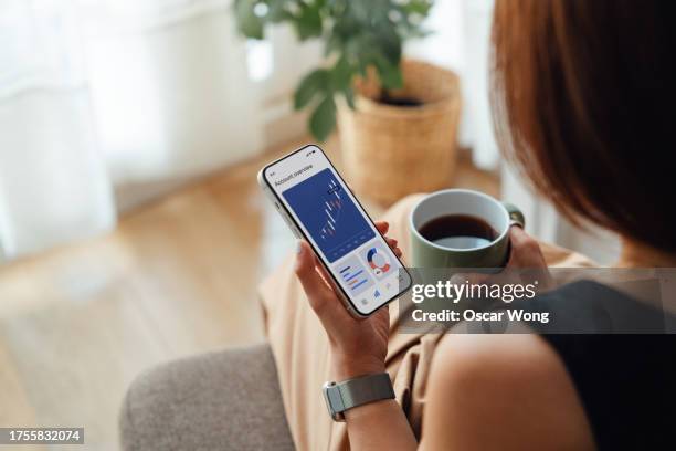 young woman managing bank account with mobile banking app on smartphone - börsenhandel finanzberuf stock-fotos und bilder