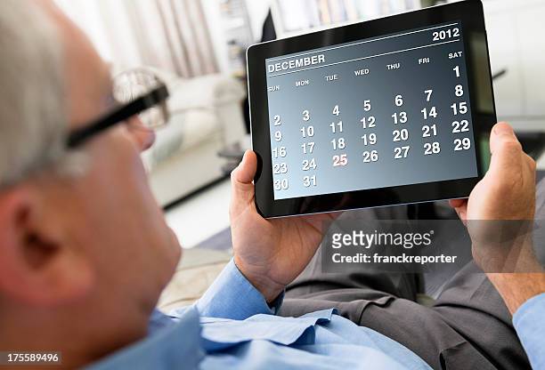 man holding a digital tablet with december 2012 calendar - 2012 calendar stock pictures, royalty-free photos & images