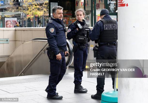 French police officers stand at the entrance of a metro station after a woman making threats on an RER train was shot and wounded by police, at the...