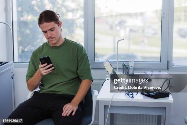 junger mann telefoniert in der arztpraxis - pharmafabrik stock-fotos und bilder