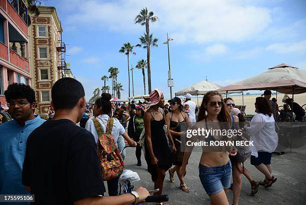 People walk on the Venice Beach boardwalk on August 4, 2013. One day earlier, Italian newlywed Alice Gruppioni was killed after a man slammed his car...