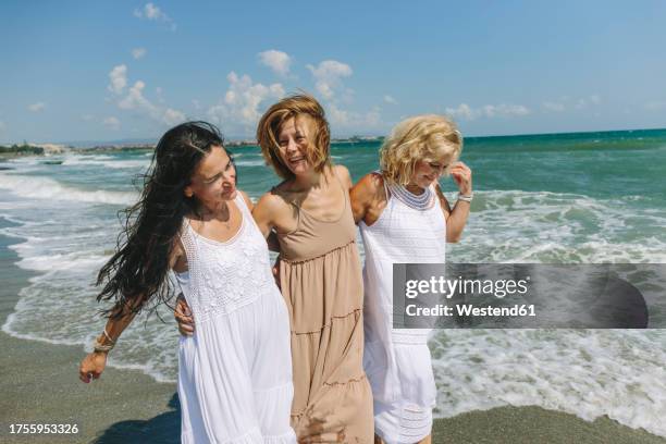 happy friends spending leisure time near shore at beach - vestido de verão imagens e fotografias de stock