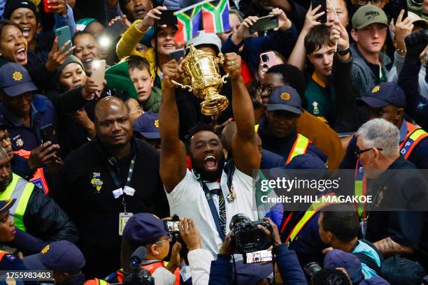 South Africa's flanker and captain Siya Kolisi holds the Webb Ellis Cup as he leaves after the South African rugby team's arrival at the OR Tambo...