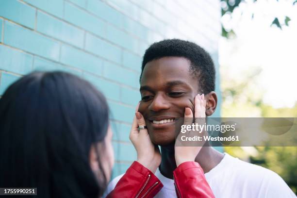 woman pulling happy boyfriend's cheeks near wall - pulling cheeks stock pictures, royalty-free photos & images