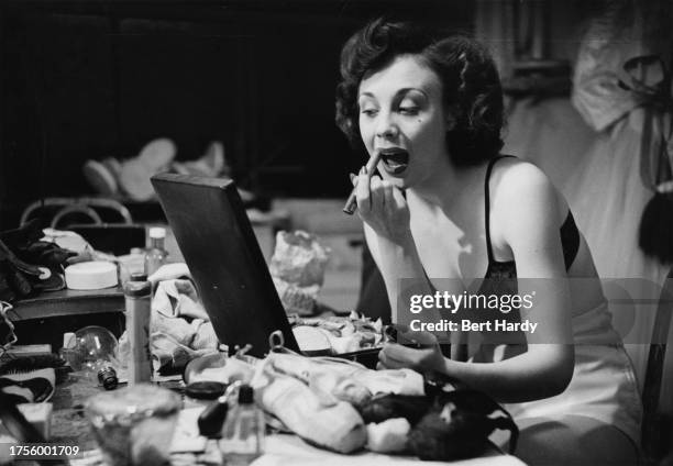 Nightclub singer wearing only her underwear as she applies lipstick at her dressing table backstage at Murray’s Cabaret Club in Beak Street, Soho,...