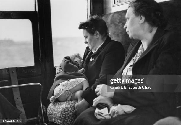 Two women, one with a young girl lying across her lap, as they travel during the Whit Monday holiday on the train from Southend-on-Sea, Essex,...