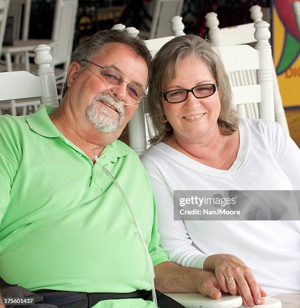 happy senior couple sitting in white wooden chairs - chronic obstructive pulmonary disease stockfoto's en -beelden