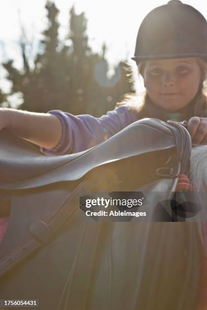 young girl getting on a horse - saddle stock pictures, royalty-free photos & images