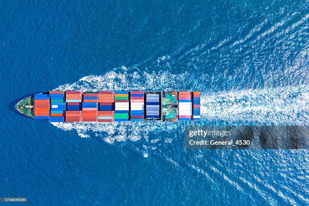 Aerial top view container ship transporting goods at blue sea.