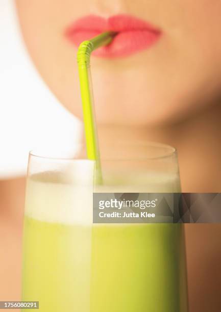 close up of a woman mouth drinking a vegetable smoothie with a straw - straw lips stock pictures, royalty-free photos & images
