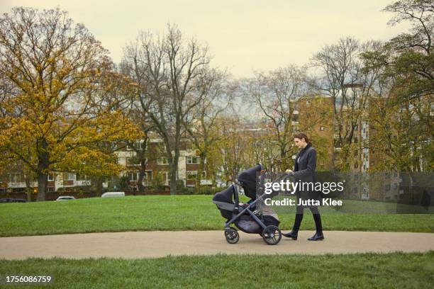 mother pushing double stroller in city park - baby pram in the park stock pictures, royalty-free photos & images