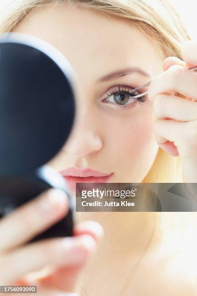 close up of young woman applying false eyelashes - eyelashes stock pictures, royalty-free photos & images
