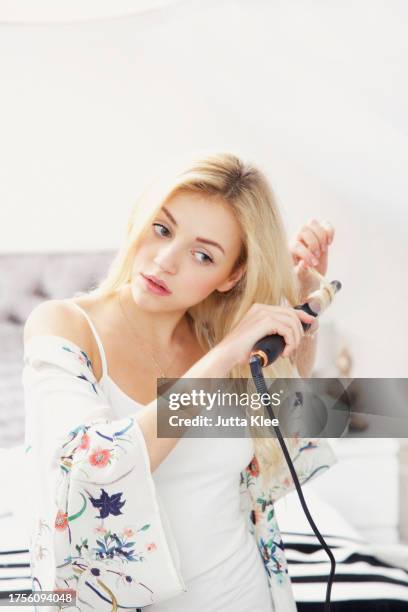 young woman using curling iron - lockenstab stock-fotos und bilder