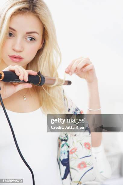 young woman using curling iron - lockenstab stock-fotos und bilder