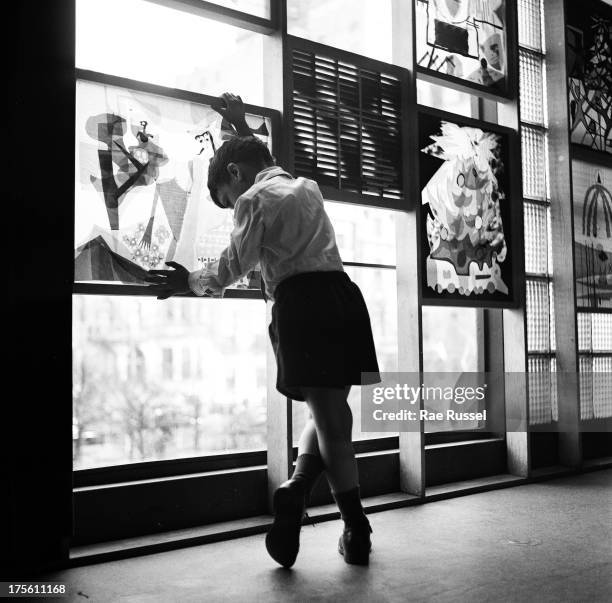 Young boy looks at artwork illuminated by light streaming from a glass window during a children's art class at the Museum of Modern Art, New York,...