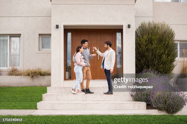 real estate agent giving key to his new home to clients - house key stock pictures, royalty-free photos & images