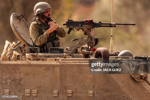An Israeli army soldier puts on his helmet as he mans a turret in an armoured tracked vehicle deployed at a position along the border with the Gaza...