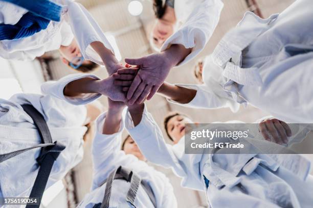 sensei y estudiantes con las manos apiladas en una clase de judo en el gimnasio - deporte de combate fotografías e imágenes de stock