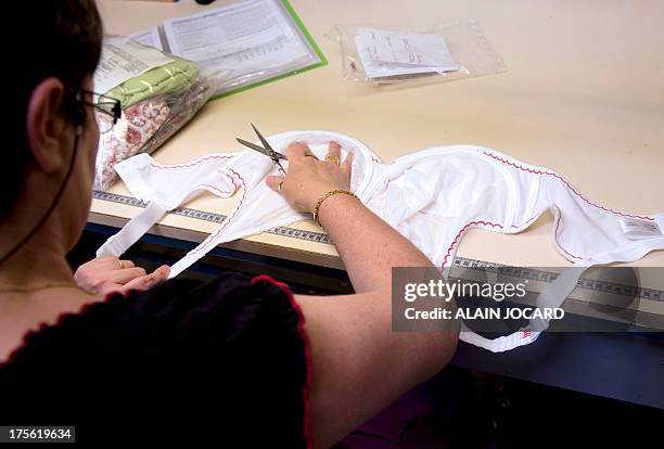 An employee of the "Indiscrete" lingerie brand checks the quality of a bra on July 1, 2013 at the company's production site in Chauvigny,...