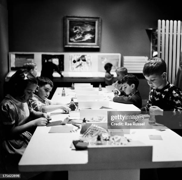 View of children seated on a long table filled with various materials during an art class as the Museum of Modern Art, New York, New York, 1948.